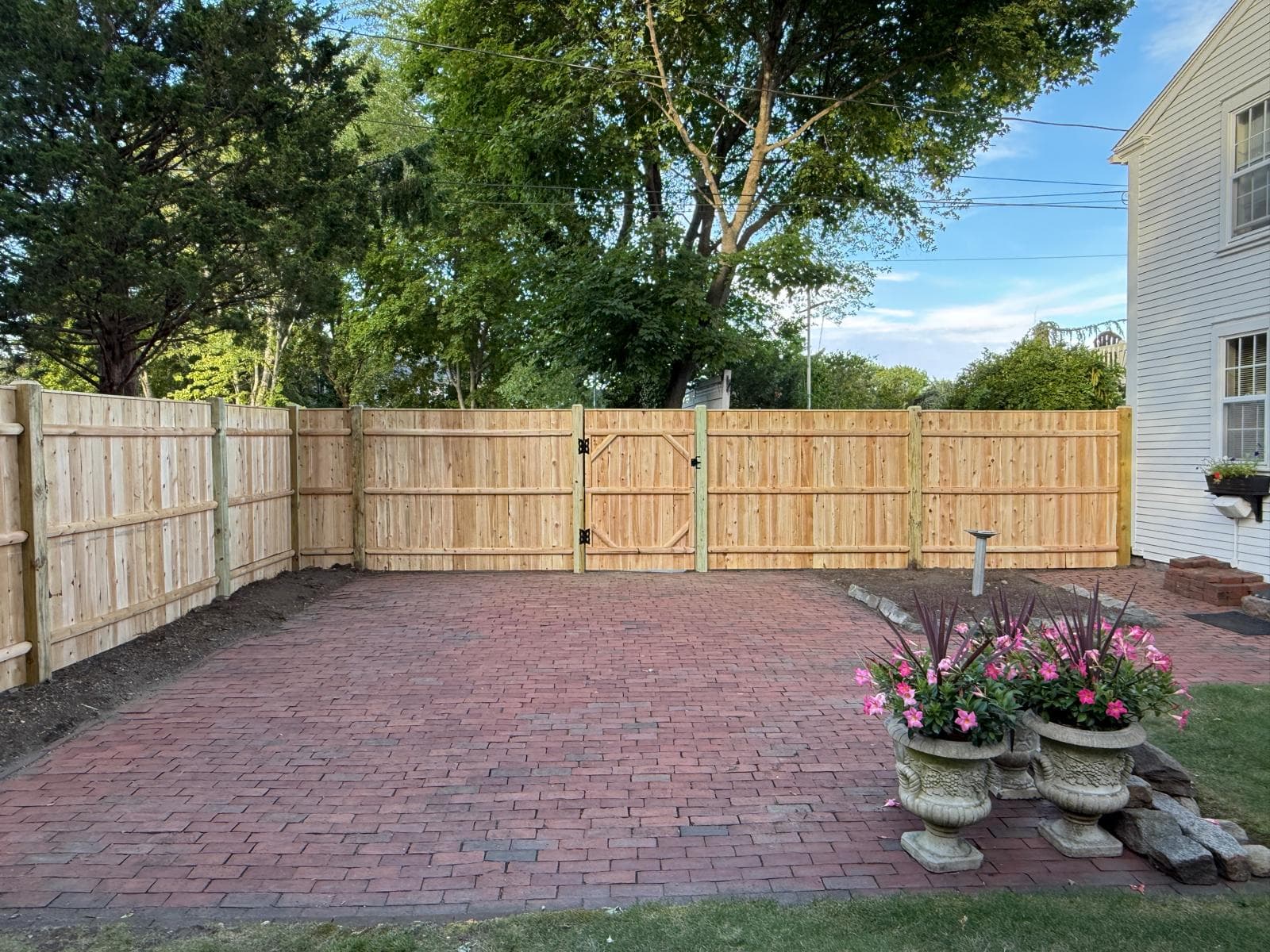 Fence installation in Massachusetts — wood privacy fence and brick patio installed by Limi Landscaping